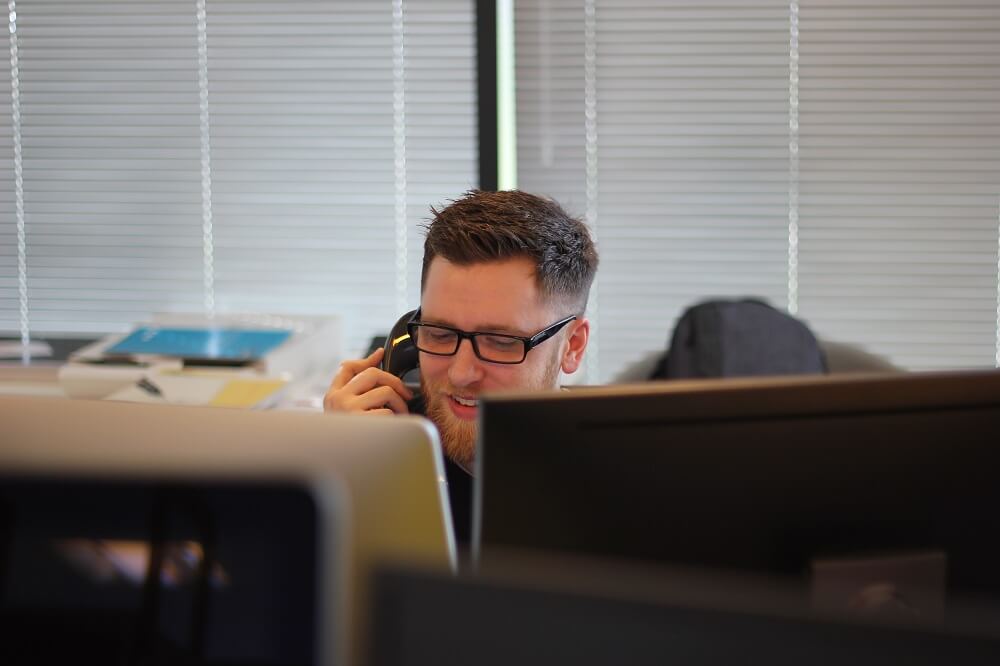 man answers phone at desk