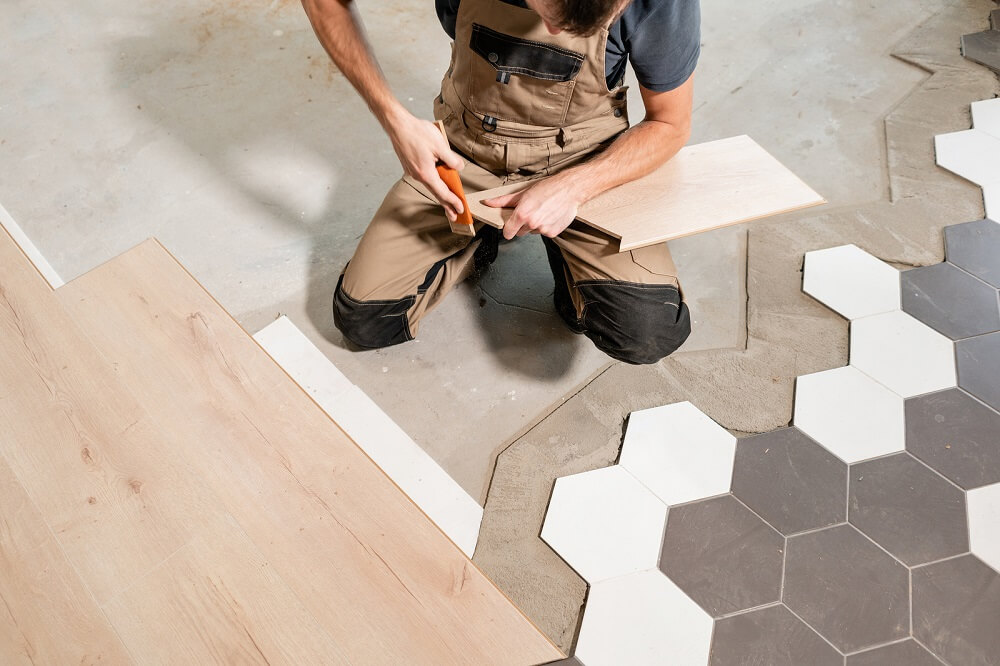 kneeling person holds wood flooring